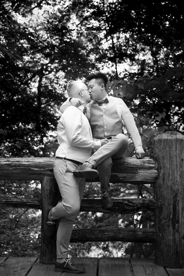 Kissing on the rustic railing in Prospect Park